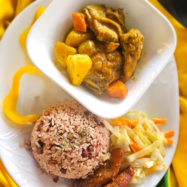 Curry chicken with potatoes and carrots, rice and peas, fried plantains, and cabbage slaw.