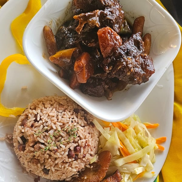 Oxtail stew with rice and peas, and a side of cabbage and carrots.