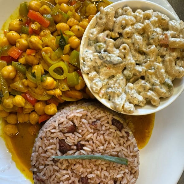 A plate of curried chickpeas, rice and peas, and creamy macaroni and cheese.
